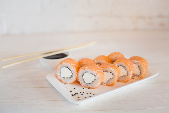 Sushi roll Philadelphia in chopsticks, closeup