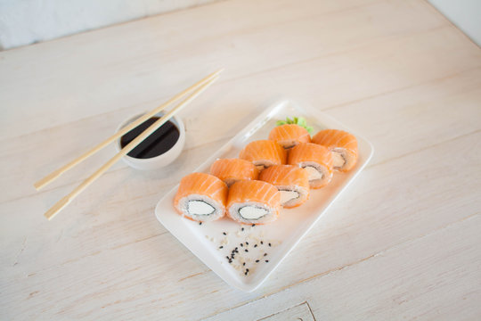 Sushi roll Philadelphia in chopsticks, closeup