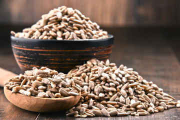 Composition with bowl of shelled sunflower seeds on wooden table
