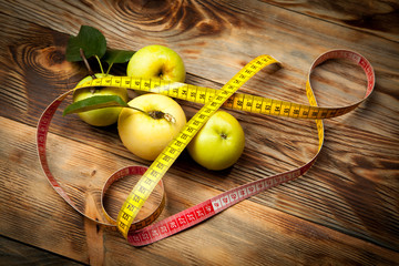 Green apples, diet and centimeter on a rustic wooden background