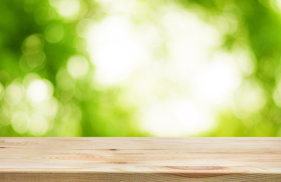 Wood table top and blur of  fresh green bokeh from garden background .For product display