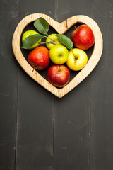 Apples in the heart on a black wooden background