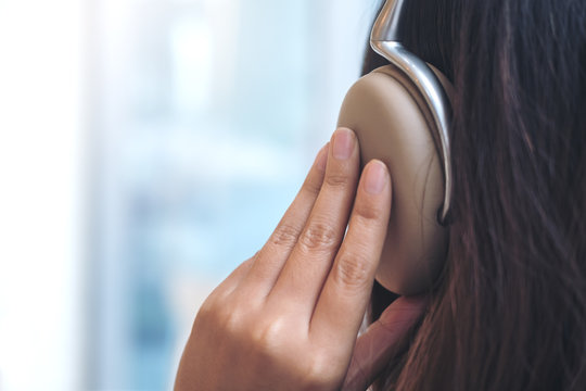 Closeup image of a woman turn back , using and holding headphone with feeling relax in modern cafe