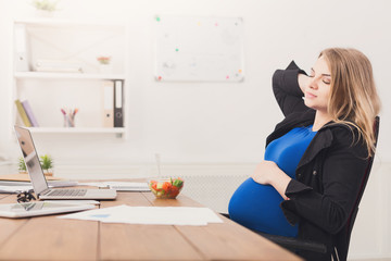 Pregnant businesswoman eating salad at office