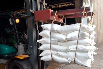 Forklift handling sugar bags outside warehouse for stuffing into container for export