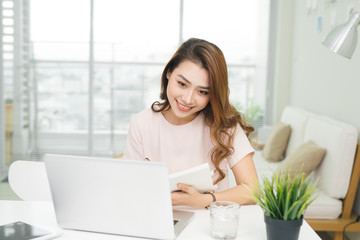 Young pretty Vietnamese woman working with laptop in office