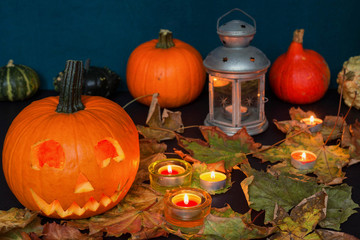 Obraz na płótnie Canvas Halloween pumpkins among candles, autumn leaves and moody old lamp