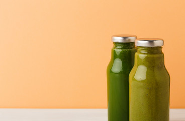 Assortment of detox smoothies in glass bottles on wall background.