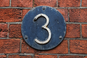 3 Digit on Dark Metal Background on red brick wall.