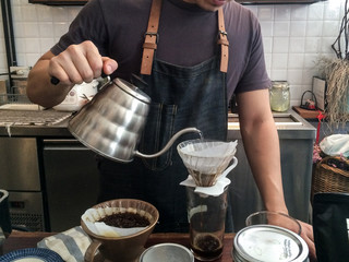 Barista making drip coffee (pour over coffee) on cafe table. Drip or pour over is vintage style in...