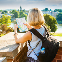 Fototapeta premium Woman stands and looking at map on background of river.