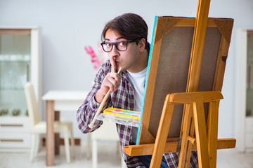 Young male artist drawing pictures in bright studio