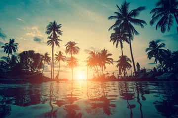 Photo sur Plexiglas Mer / coucher de soleil Silhouettes of palm trees during an amazing sunset on a tropical beach.