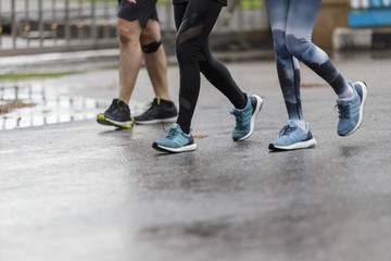 Marathon runners focus clear running shoes on the street with rain.