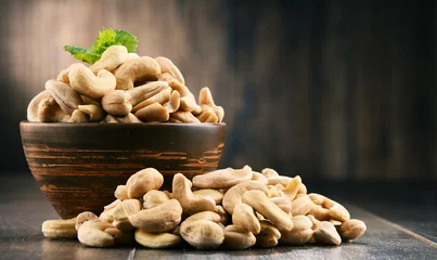 Foto op Aluminium Bowl with cashew nuts on wooden table © monticellllo