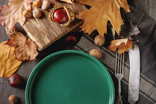 Decorating for Halloween. Autumn card. Green plate, chestnuts, nuts, leaves. free space text.