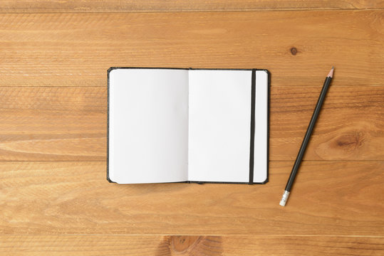 Cuaderno abierto y l&aacute;piz en el suelo de madera