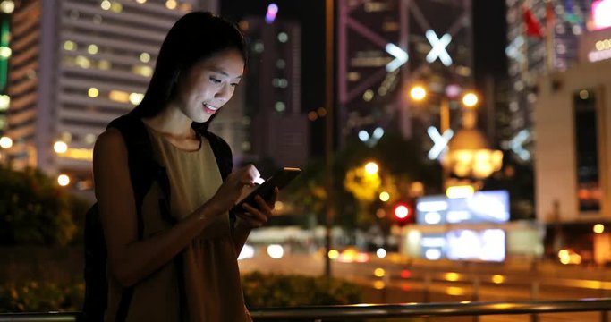 Asian woman working on cellphone in city at night