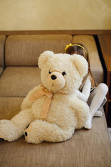 Little girl hiding behind big teddy bear in her room