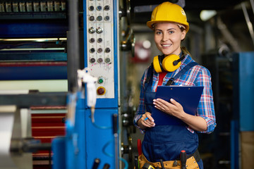 Portrait of cheerful young warehouse employee looking at camera with charming smile while doing...