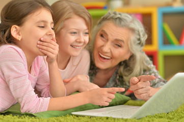 senior woman with granddaughters using laptop