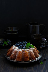 Vanilla cake (gugelhupf) with blueberries. dark background.