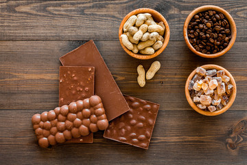Fototapeta premium Chocolate with nuts on dark wooden background top view copyspace