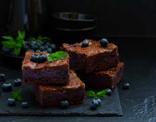 Chocolate brownies with blueberries and cream filling. Dark background.