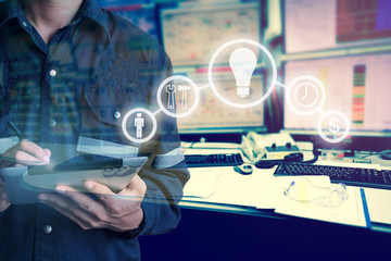 Double exposure of Engineer or Technician man with business industrial tool icons while using tablet with monitor of computers room  for oil and gas industrial business concept