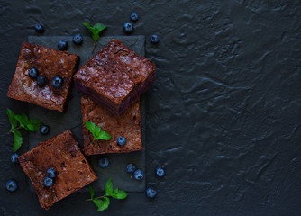 Chocolate brownies with blueberries and cream filling. Dark background.