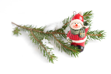 New Year's background. Christmas background. Christmas tree toy in the form of a snowman, a branch of spruce isolated on white background. Snow on the Christmas tree.