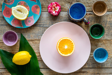 Crockery pattern. Cups and plates near tropical leaves and fruits on wooden background top view