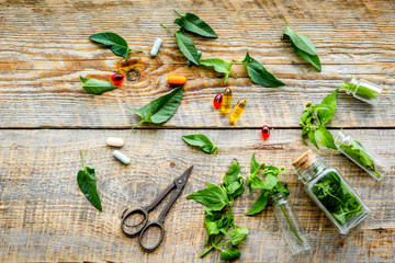 Harvest medicinal herb. Leaves, bottles and sciccors on wooden background top view