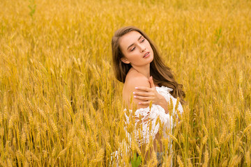 Portrait of a young girl on a background of golden wheat field