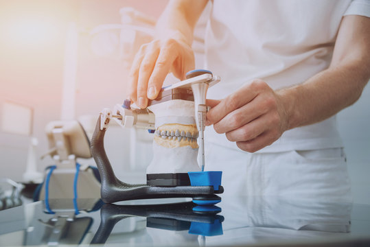 Dental technician working with articulator in dental lab