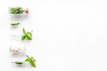 Medicinal herb in bottles on white background top view copyspace
