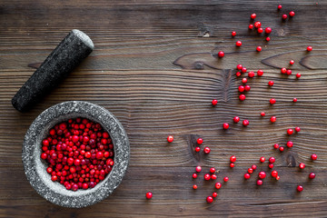 mortar with berries, herbs and spices ingredients on wooden background top view