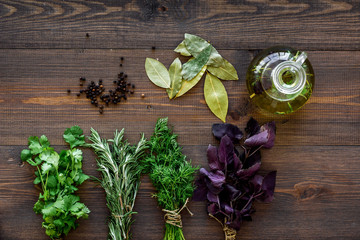 natural oil and fresh greenery for restaurant cooking on wooden kitchen table background top view