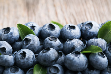 Ripe blueberries with green leafs on wooden table