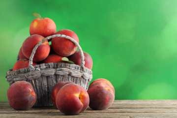 Sweet nectarines in basket on grey wooden table