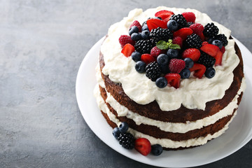 Delicious chocolate biscuit cake with berries on grey wooden table