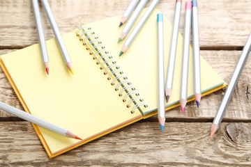 Drawing colourful pencils with notebook on brown wooden table