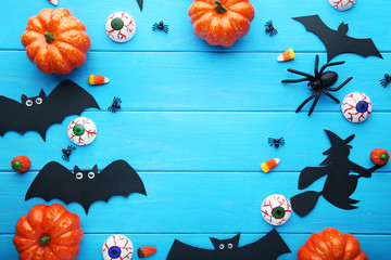 Halloween bats with pumpkins on blue wooden table