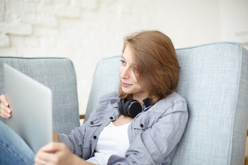 Happy woman resting on comfortable sofa in living room, spending day-off using electronic gadget, enjoying online communication, browsing websites, chatting with friends making video conference call