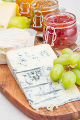 wooden cutting board with cheese and jams