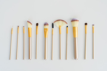 Makeup silver and gold brushes row on white background