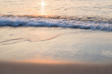 Fototapeta na wymiar Sunset soft beautiful ocean wave on sandy beach. romantic travel background.
