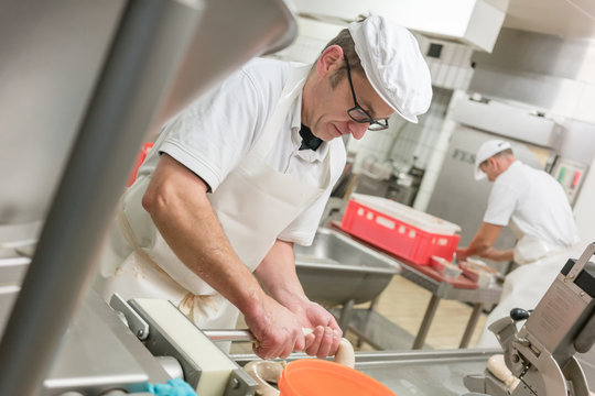 Butcher in butchery filling sausages