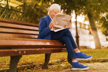 Autumn, boy in the Park reading a newspaper