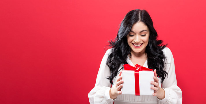  Happy young woman holding a gift box on a solid background